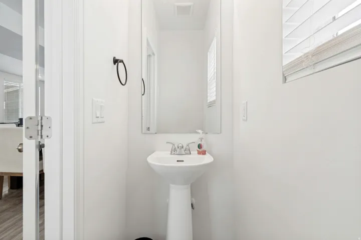 Pedestal sink with chrome faucet, complemented by a wall-mounted mirror