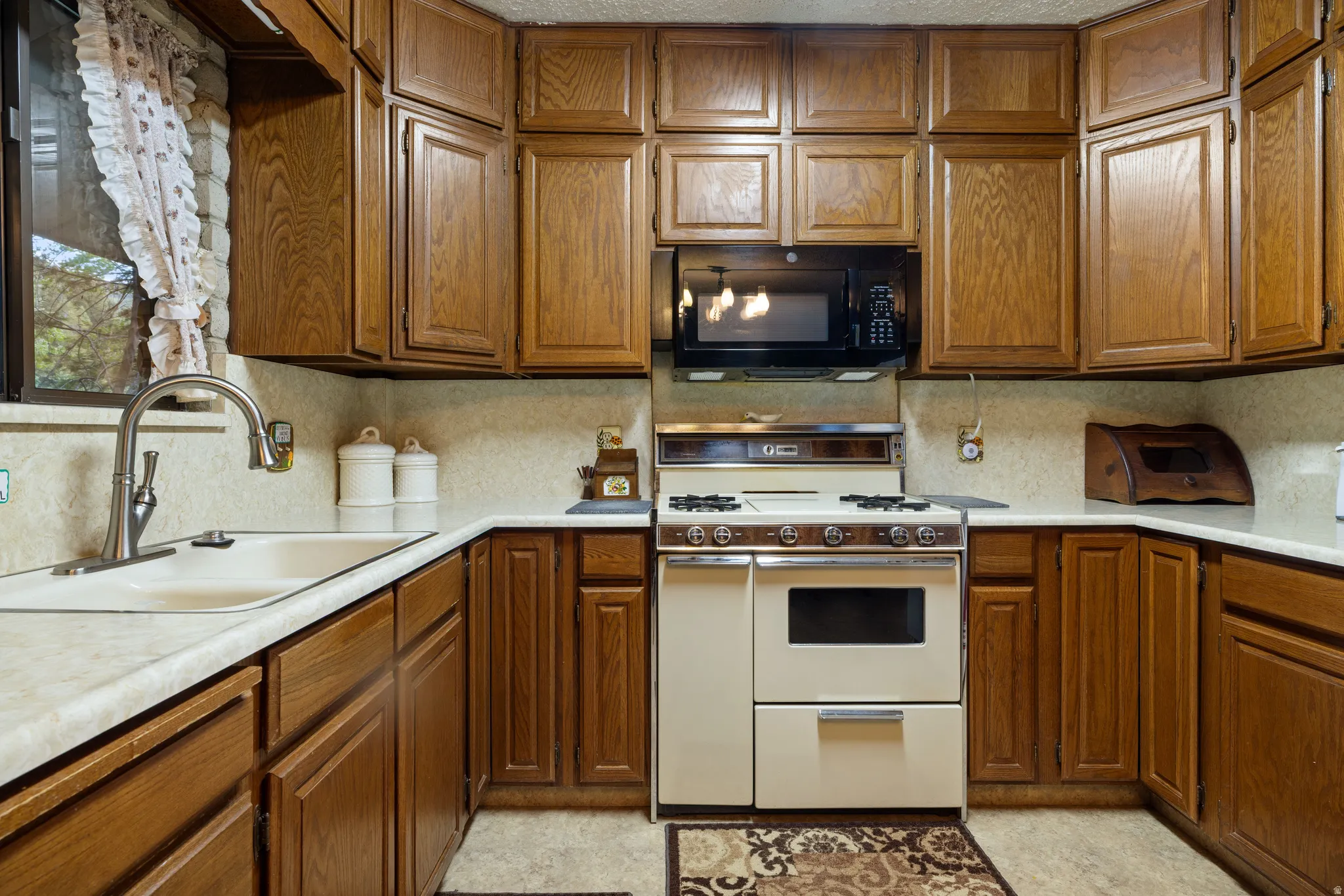 Kitchen featuring wood cabinetry, light-toned countertops, a built-in microwave, and a range with an oven
