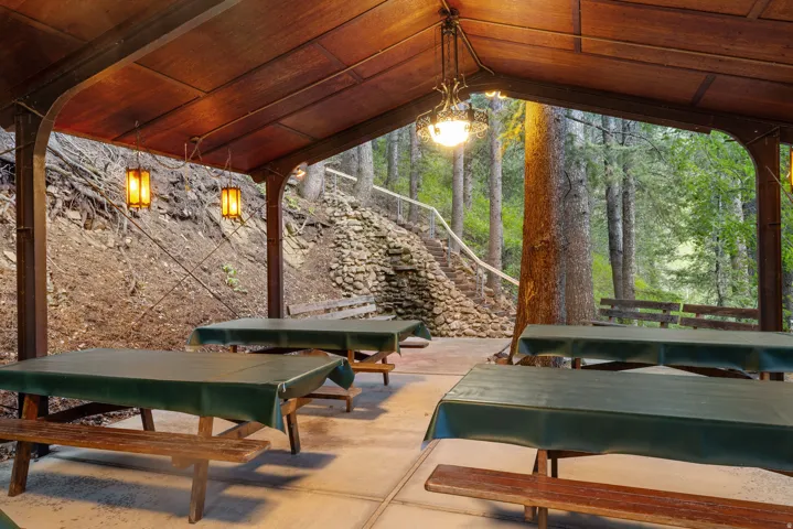Covered patio area featuring a sloped wood-paneled ceiling, exposed support beams, and concrete flooring