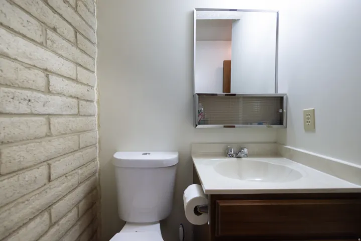 Bathroom featuring a light-colored brick accent wall