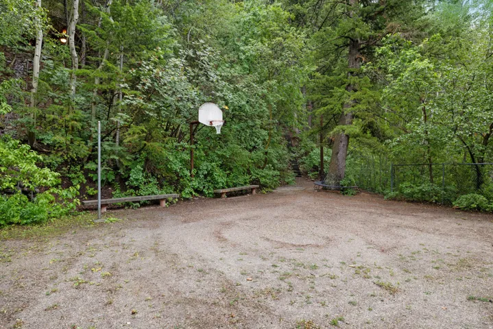 Outdoor recreational area featuring a basketball hoop and volleyball court, two benches, and a flat surface.