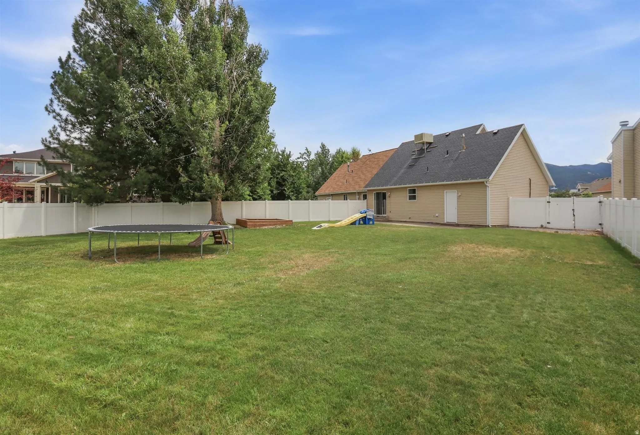 Expansive green lawn surrounded by a white vinyl privacy fence