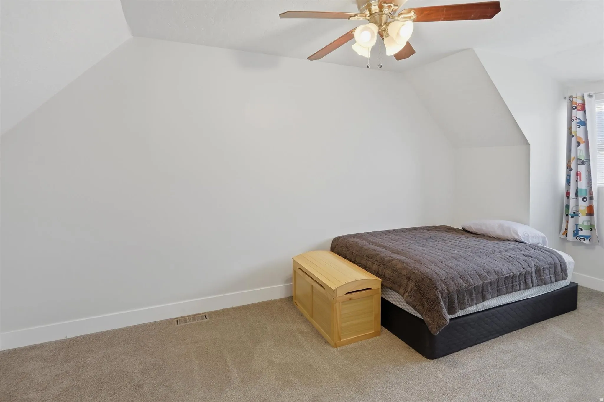 Room featuring an angled ceiling, soft carpet flooring, and a ceiling fan with integrated lighting
