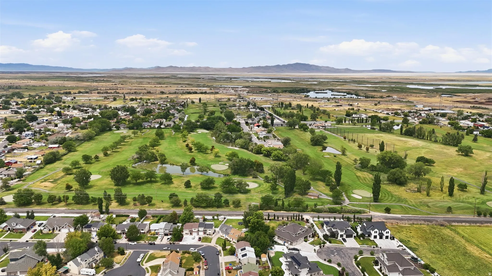 Aerial perspective showcasing a verdant golf course with multiple fairways and water features, surrounded by established residential areas