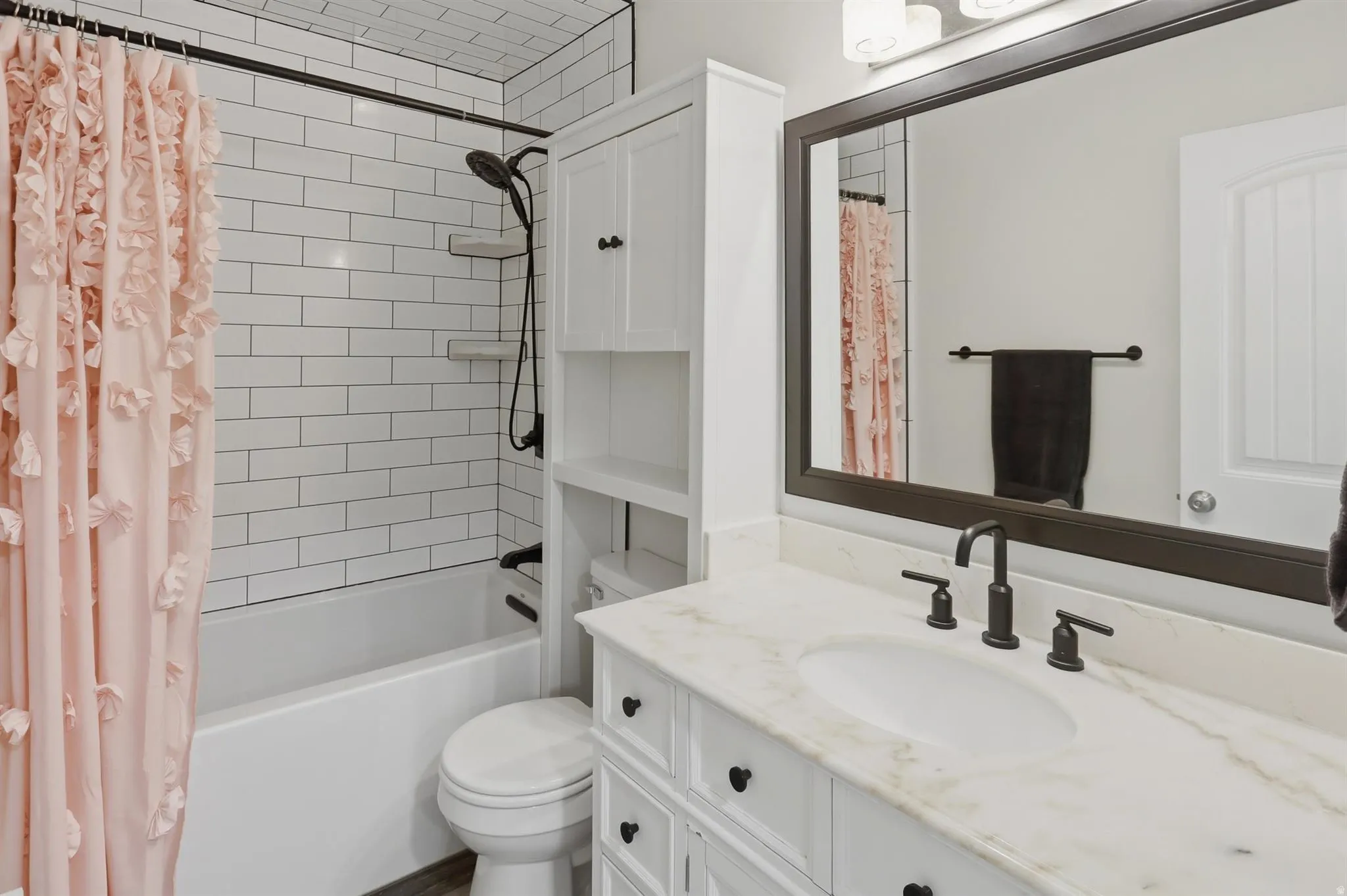 Bathroom vanity featuring a white undermount sink, stone countertop, and dark-finish faucet