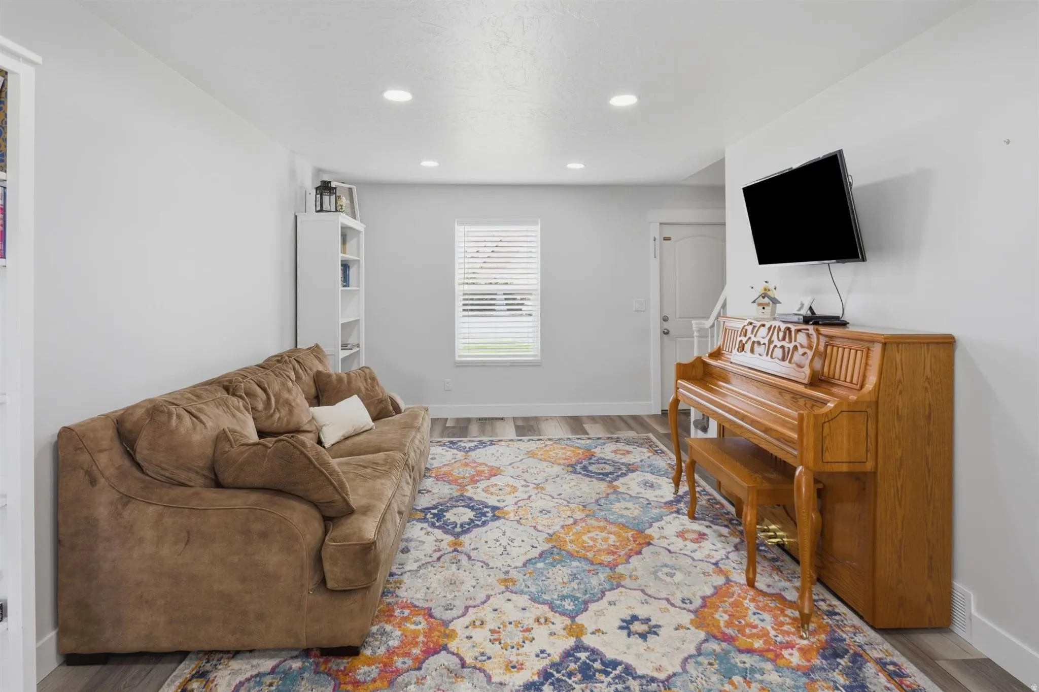 Spacious living area featuring light gray walls, recessed lighting, and wood-finish flooring