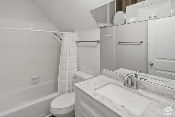 Bathroom featuring a single vanity with a white countertop and undermount sink, a toilet, a shower-over-tub combination with white subway tile surround, and a wall-mounted mirror