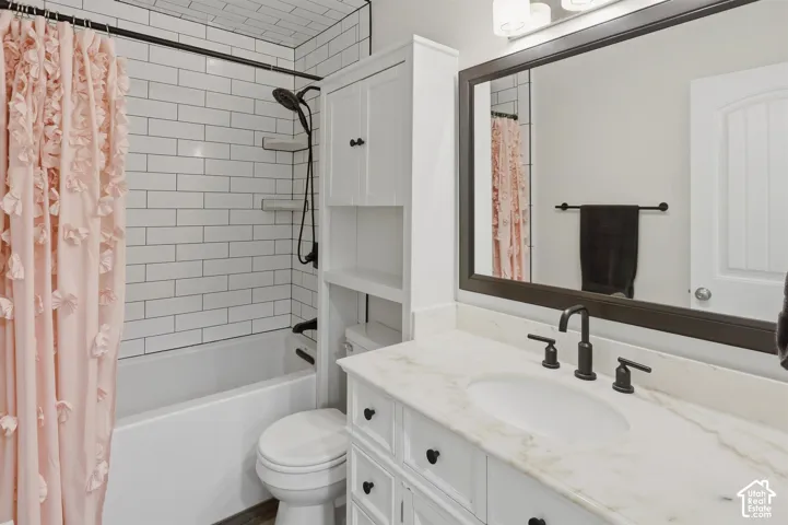 Bathroom vanity featuring a white undermount sink, stone countertop, and dark-finish faucet
