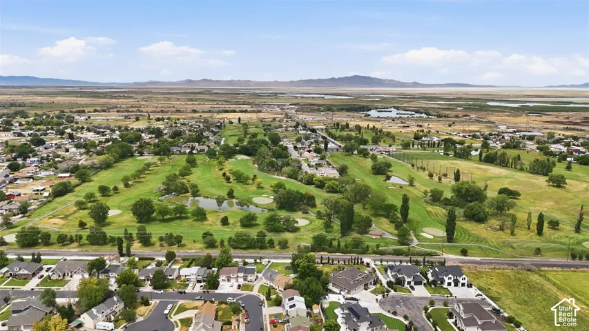 Aerial perspective showcasing a verdant golf course with multiple fairways and water features, surrounded by established residential areas