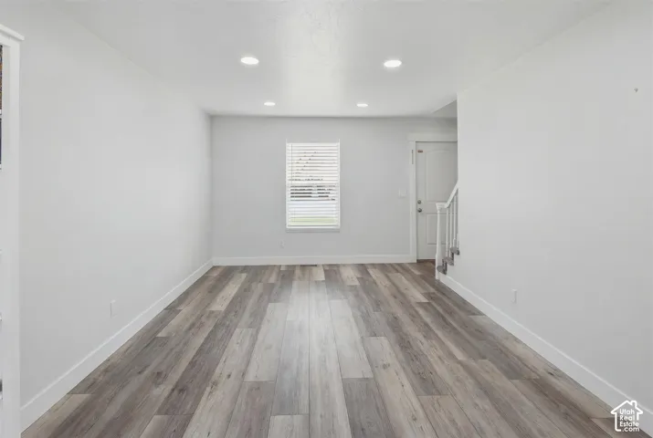 Spacious room with wood-finish flooring, white baseboards, and neutral wall tones