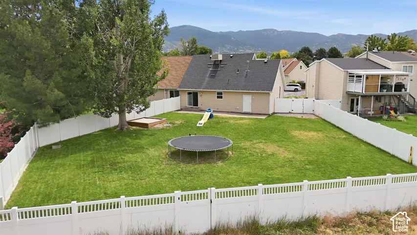 Expansive backyard featuring a manicured lawn, established trees, and a full perimeter fence