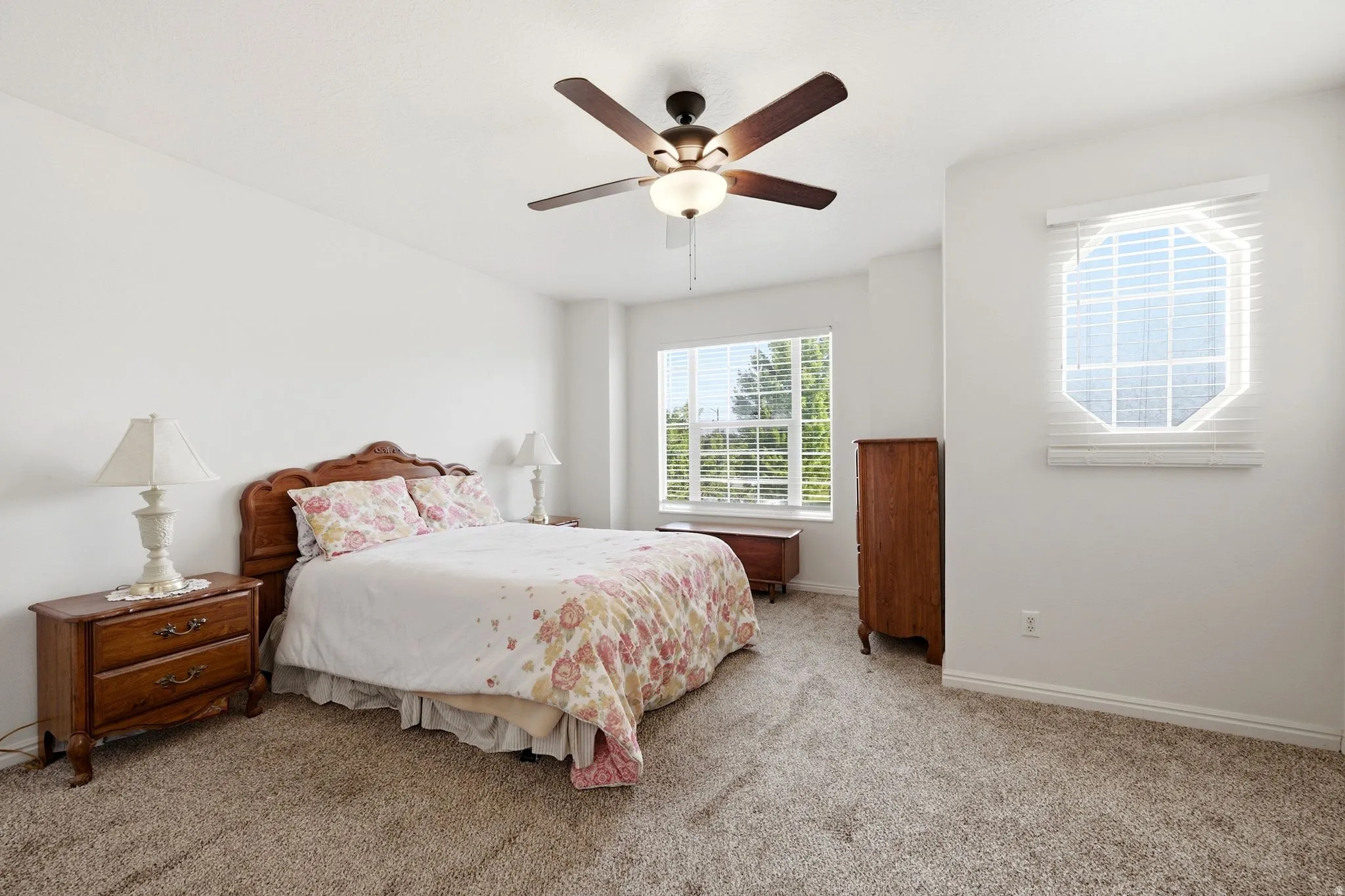 Carpeted interior with a ceiling fan, a large window, and an octagonal window