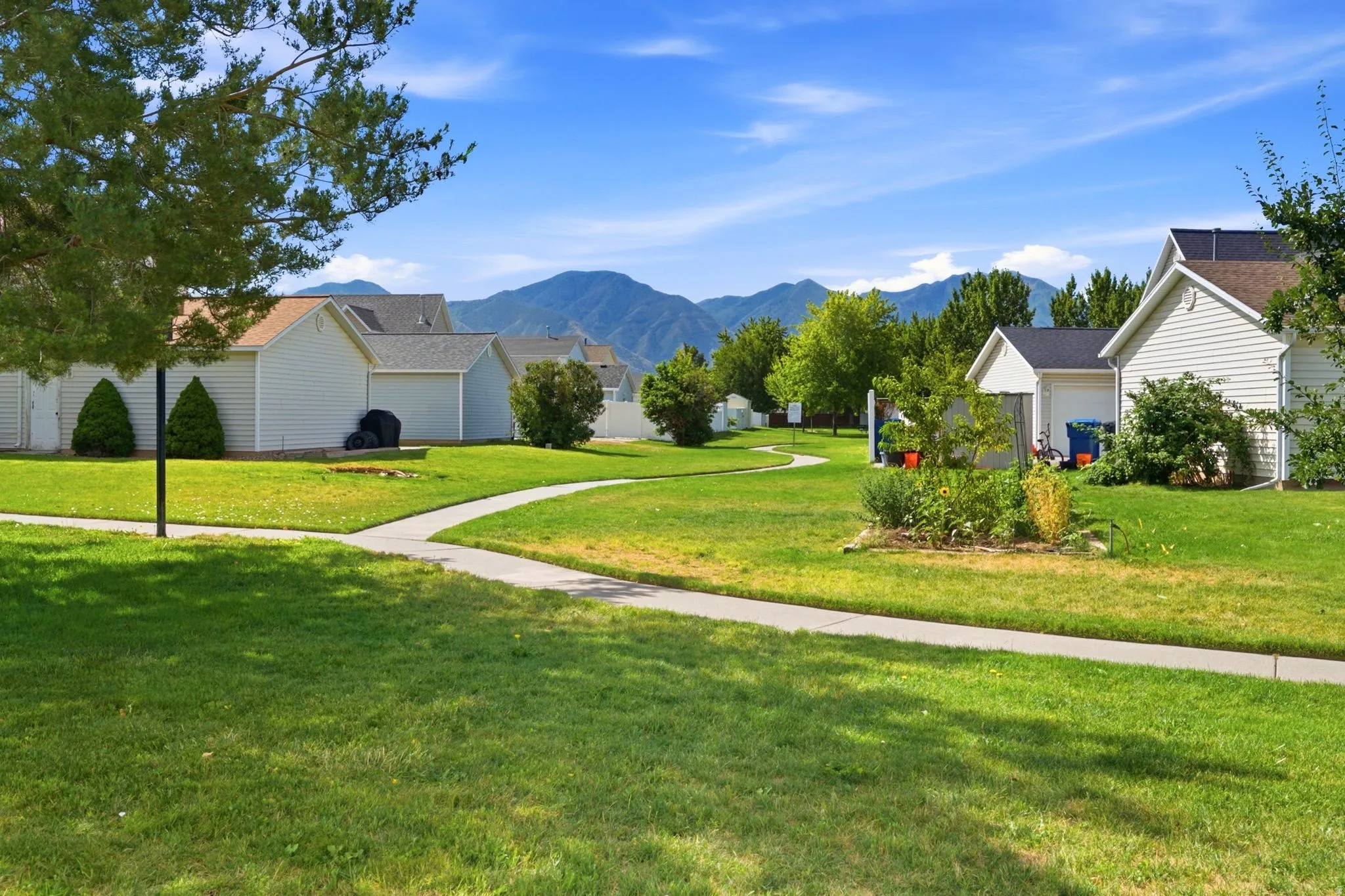 Expansive green space featuring a winding concrete pathway and distant mountain scenery