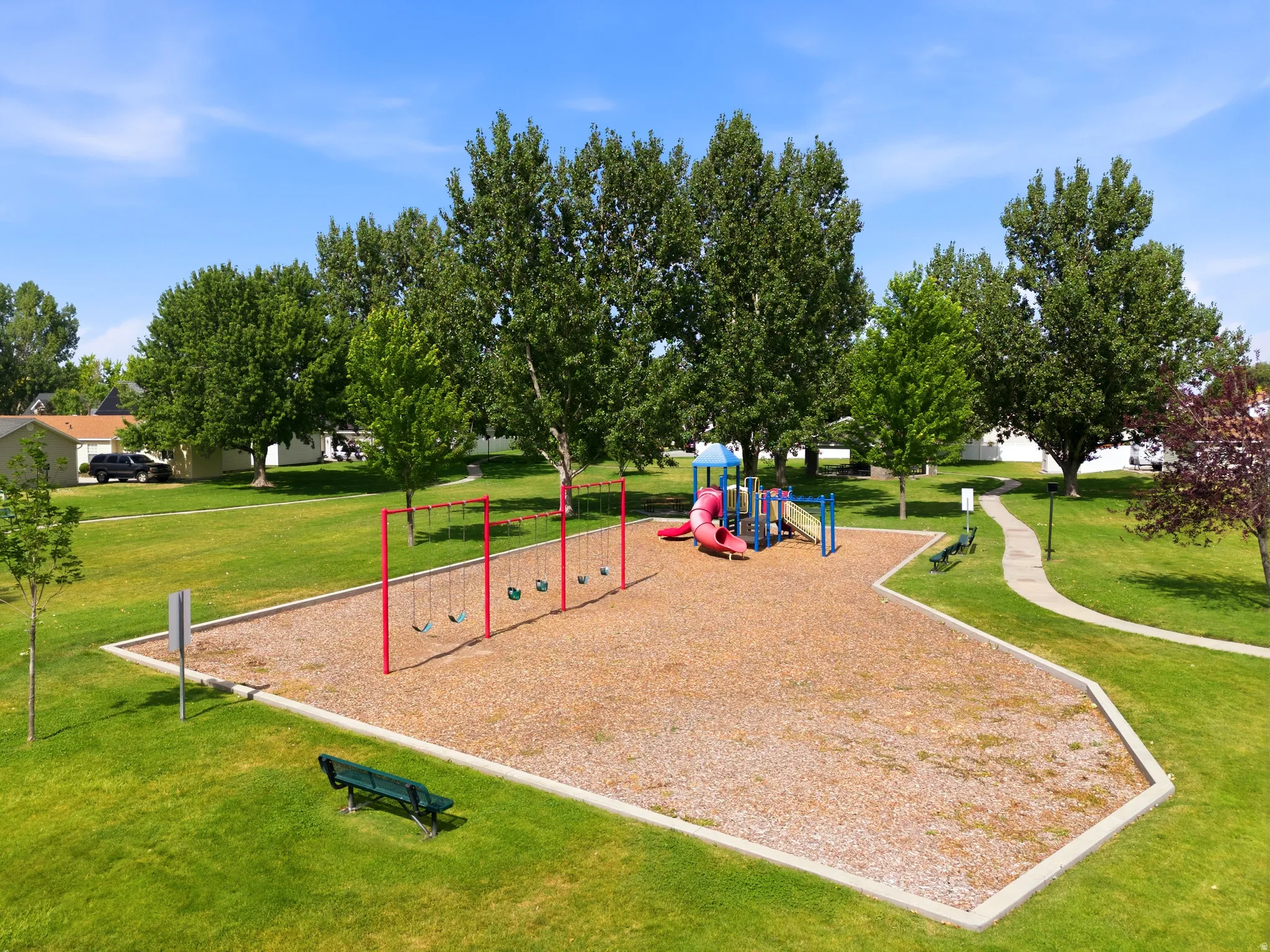 Playground area featuring a swing set, slide structure, and wood chip surfacing