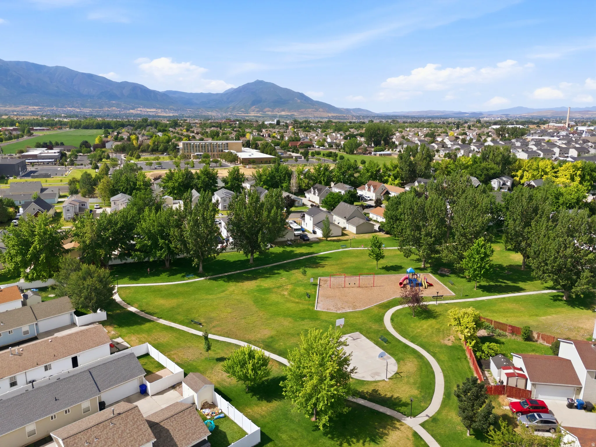 Expansive community park featuring a playground, basketball half-court, and walking paths