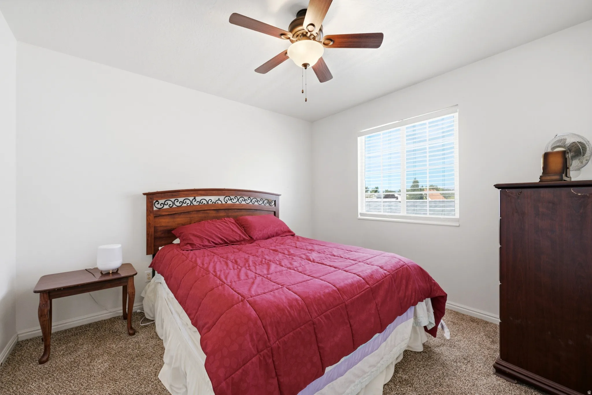 Bedroom featuring neutral wall paint, carpet flooring, a ceiling fan with integrated lighting, and a window with blinds