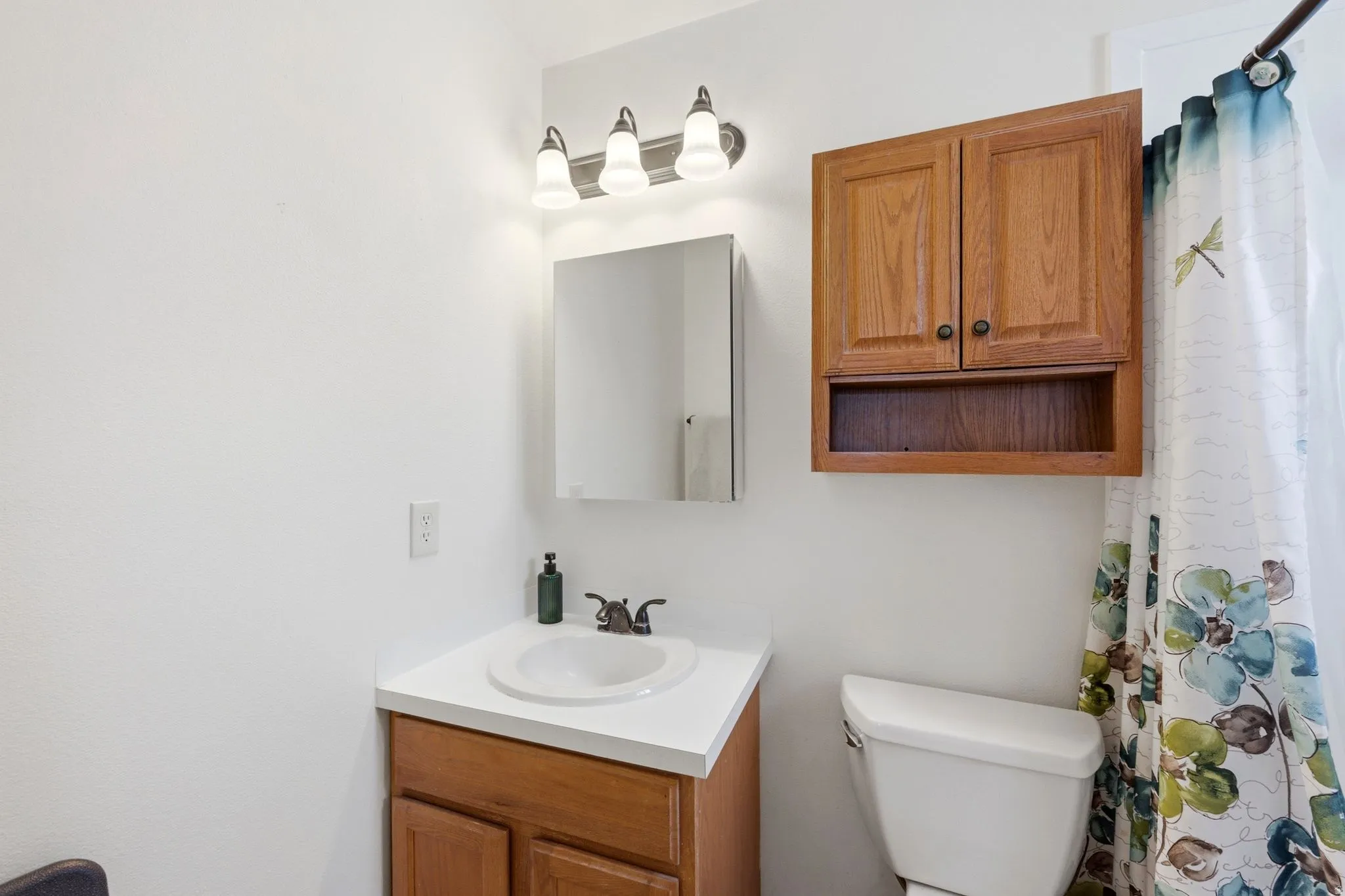 Bathroom vanity featuring a white countertop, undermount sink, and wood-finish cabinetry