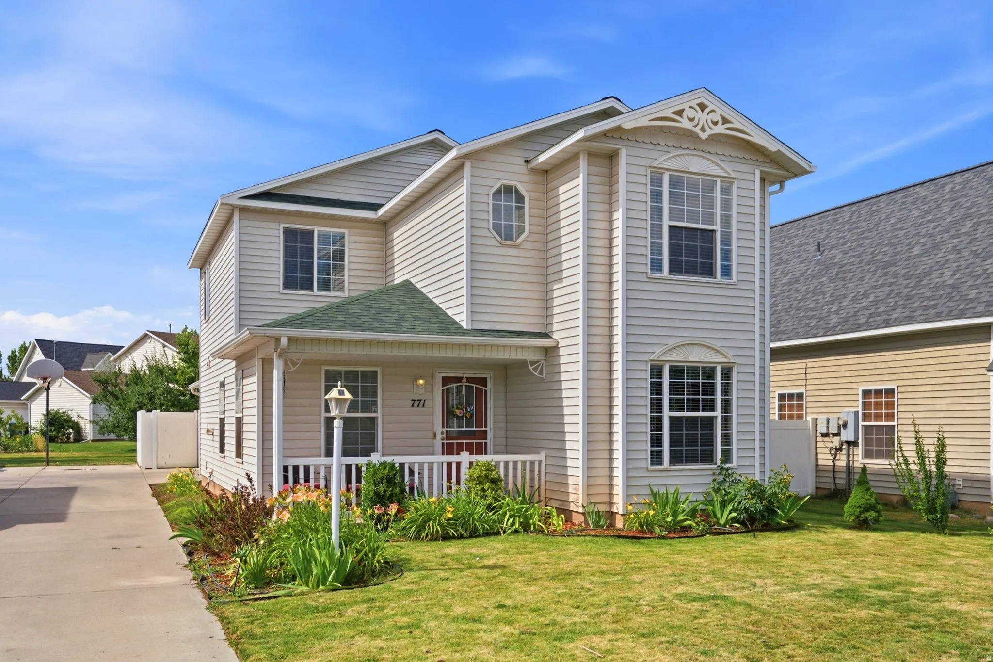 Two-story residence featuring light-colored siding and a contrasting green-shingled roof over the covered front porch