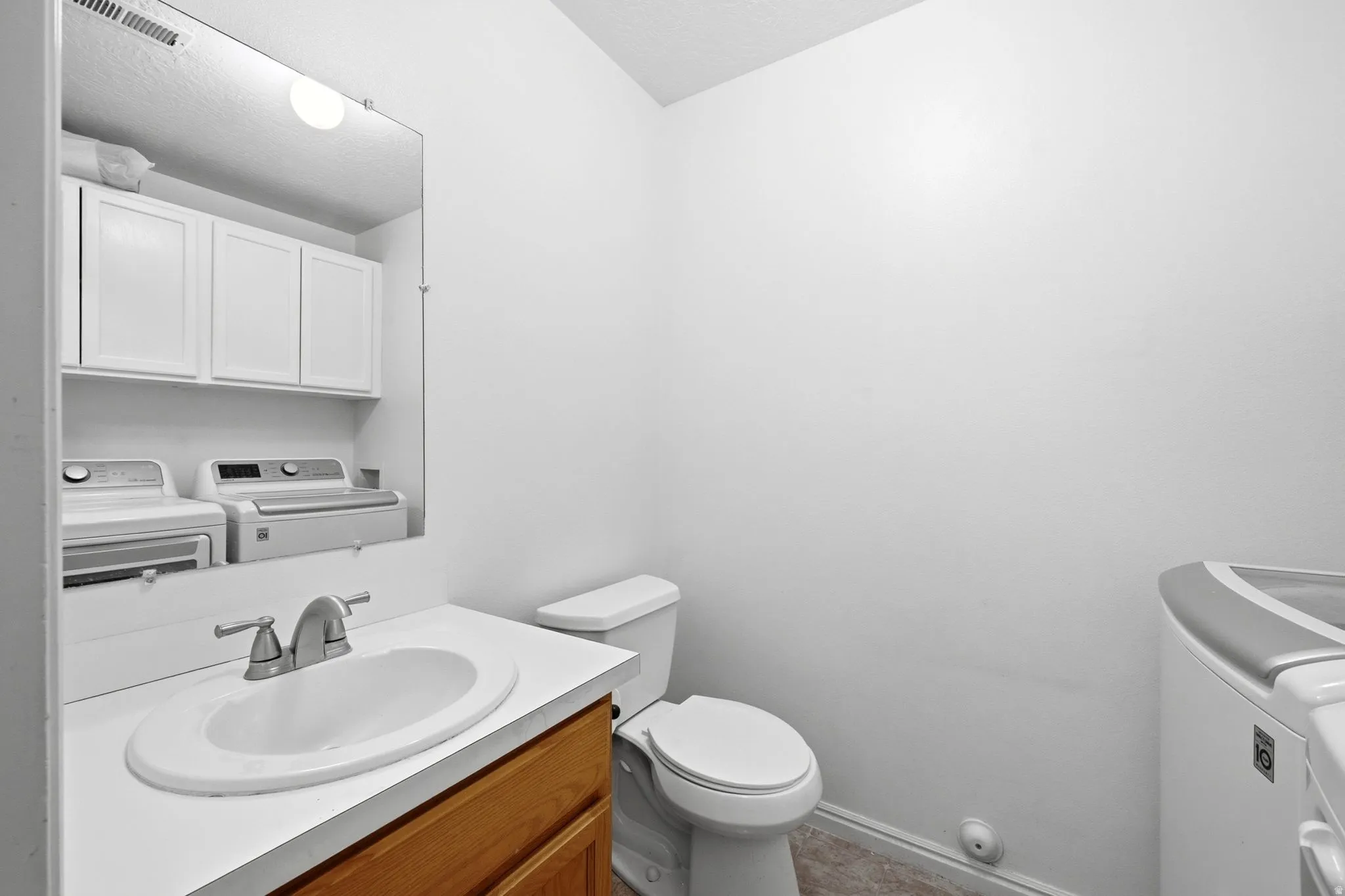 Bathroom vanity featuring a white countertop with an integrated oval sink, a brushed nickel faucet, and a wood-finish cabinet