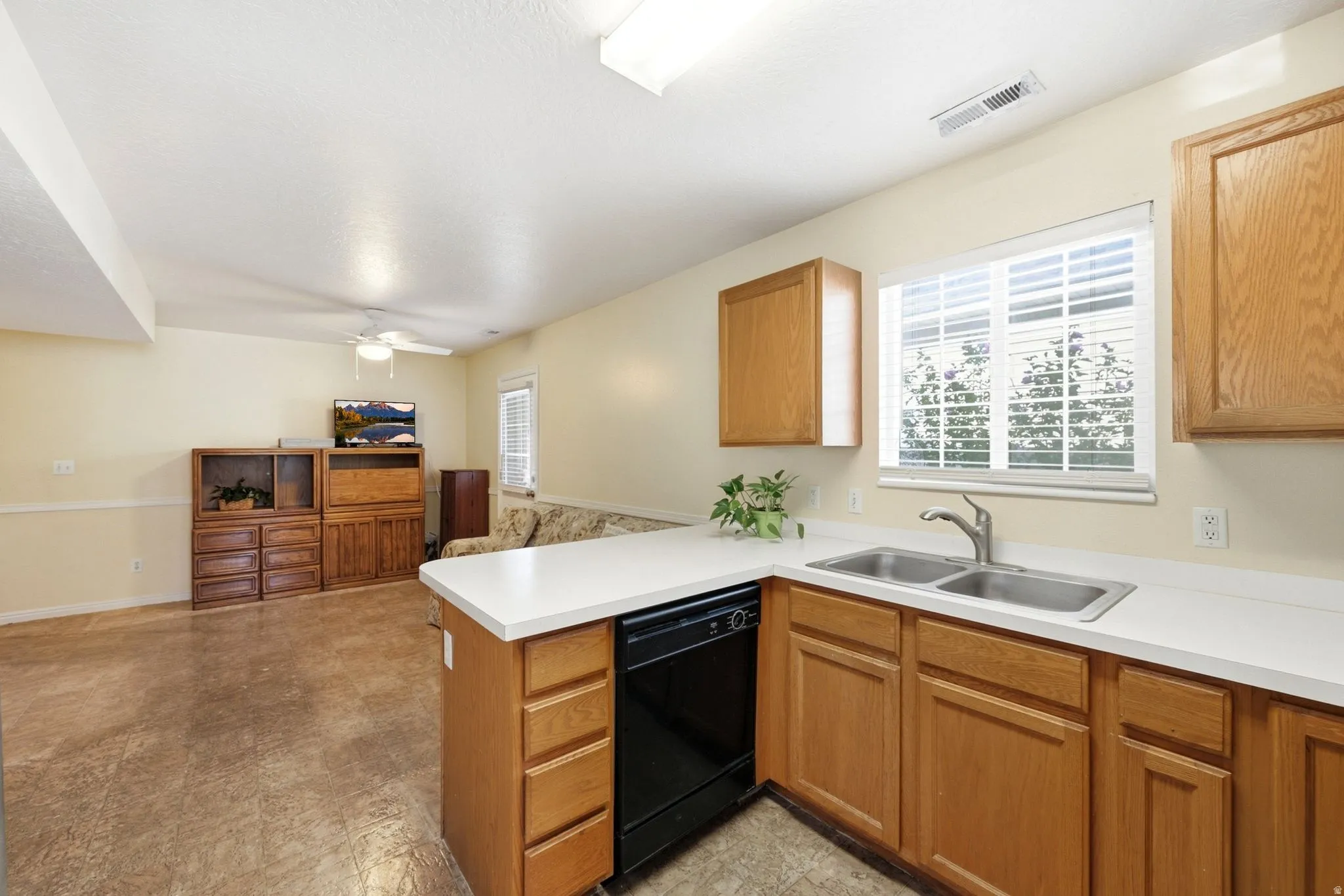 Kitchenette featuring a double basin stainless steel sink, black dishwasher, and white countertops