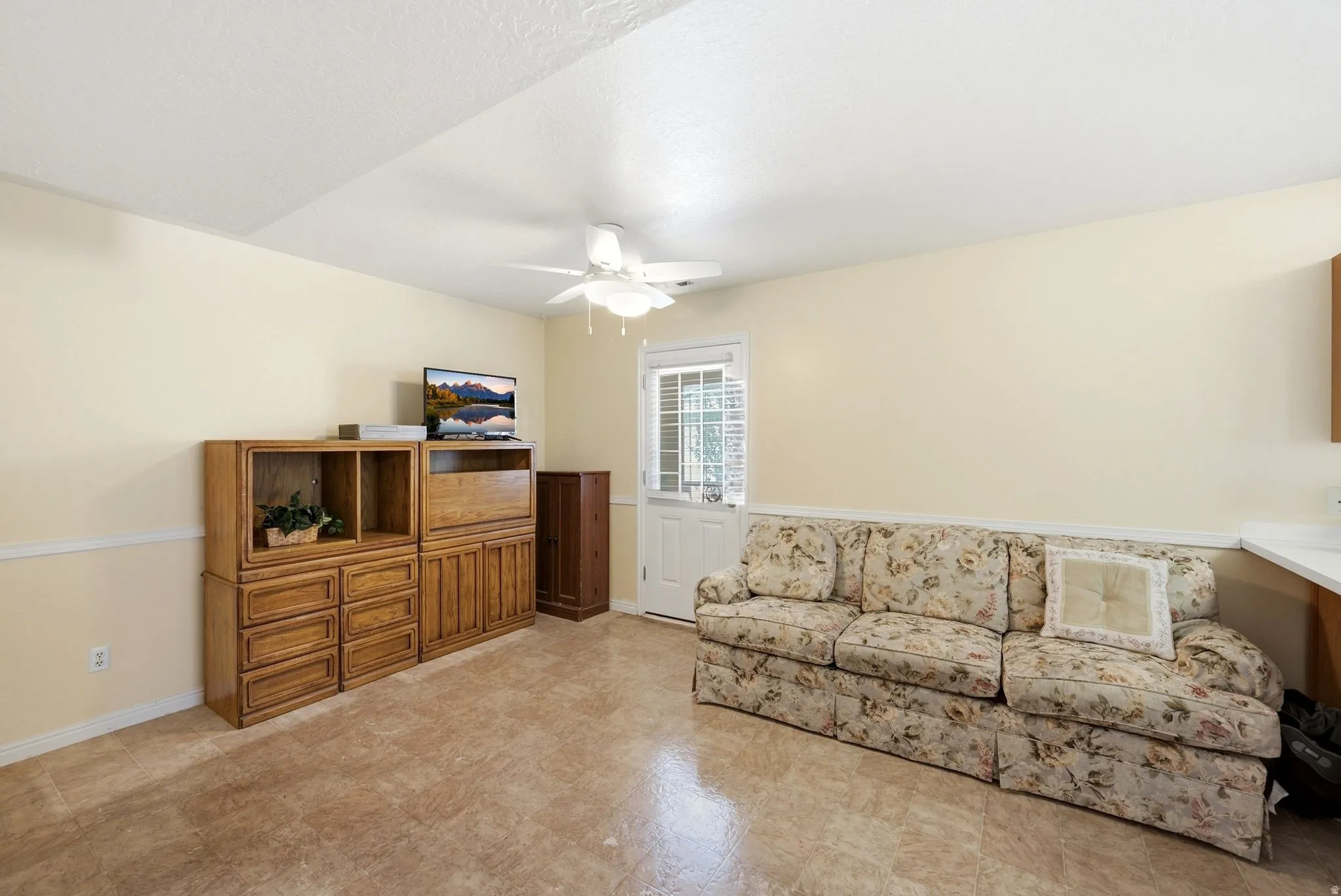 Open concept room featuring two-tone wall paint, a white ceiling fan with light fixture, and light-toned flooring