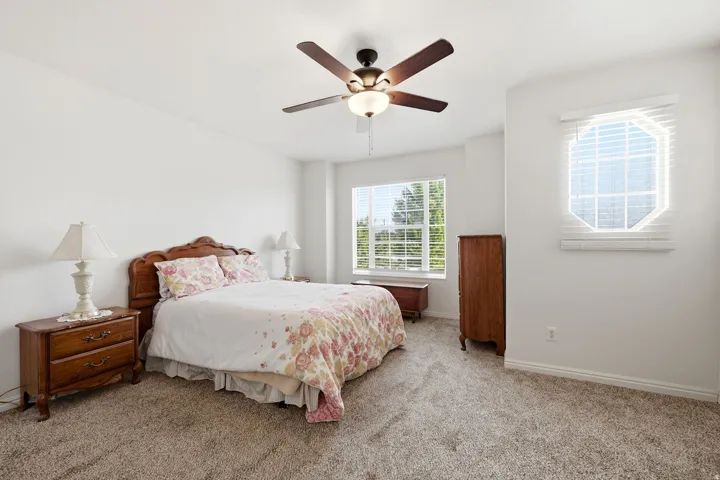 Carpeted interior with a ceiling fan, a large window, and an octagonal window