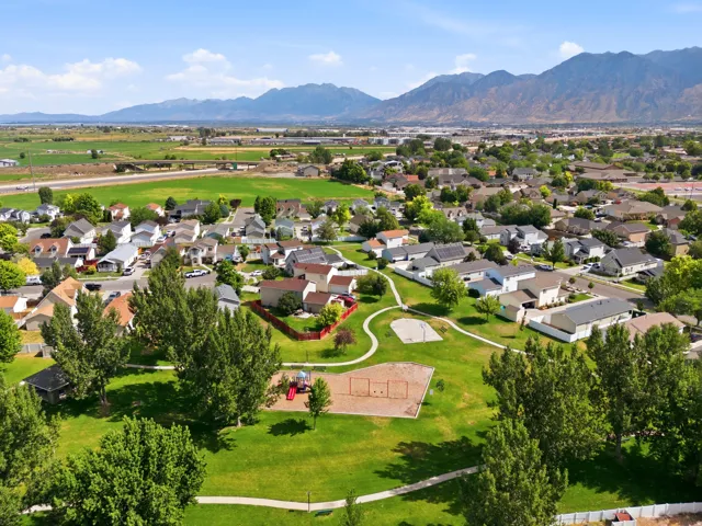 Expansive community green space with mature trees, paved walking paths, and a playground
