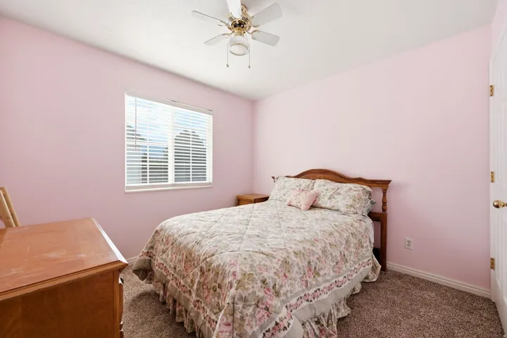 Bedroom featuring a ceiling fan, window with horizontal blinds, and textured wall finish