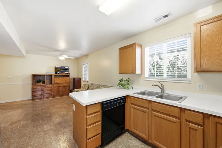 Kitchenette featuring a double basin stainless steel sink, black dishwasher, and white countertops