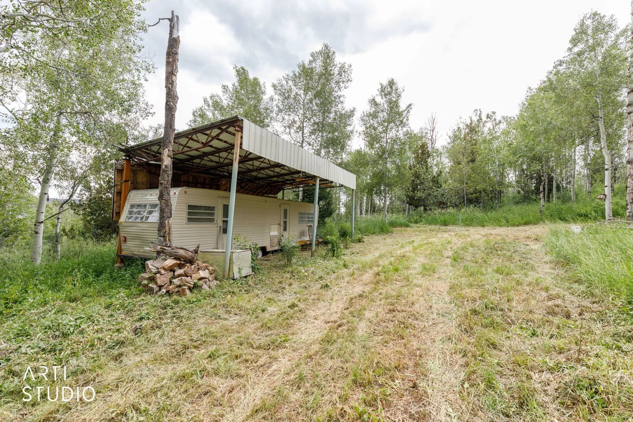 Open land featuring natural vegetation and a partial metal canopy structure
