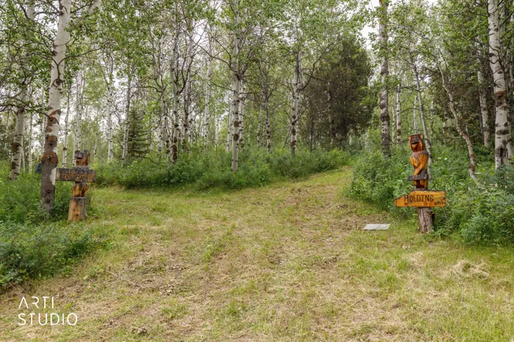 Wooded property entrance featuring two carved wooden figures and a path