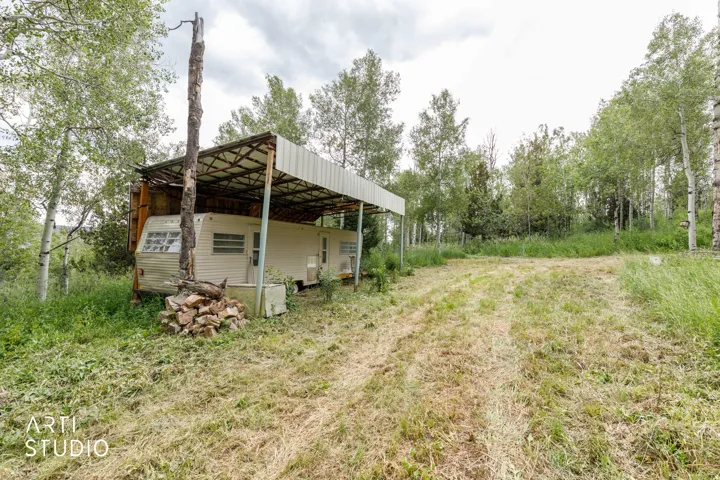 Open land featuring natural vegetation and a partial metal canopy structure