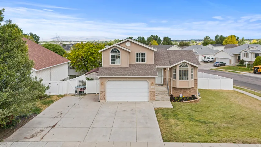 Two-story residential property featuring a neutral stucco exterior with stone accents, a two-car garage, and a large concrete driveway