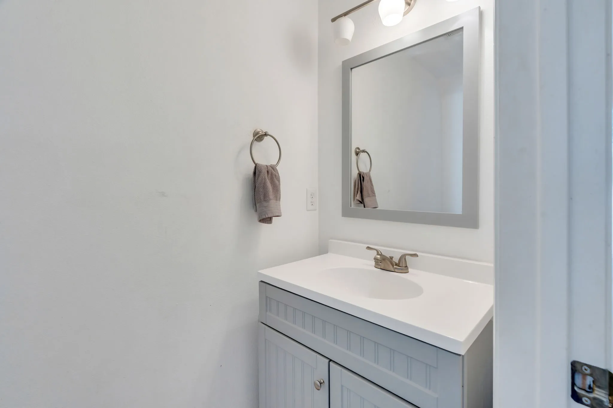 Vanity featuring a white countertop with an integrated sink, brushed nickel faucet, and beadboard-style cabinetry