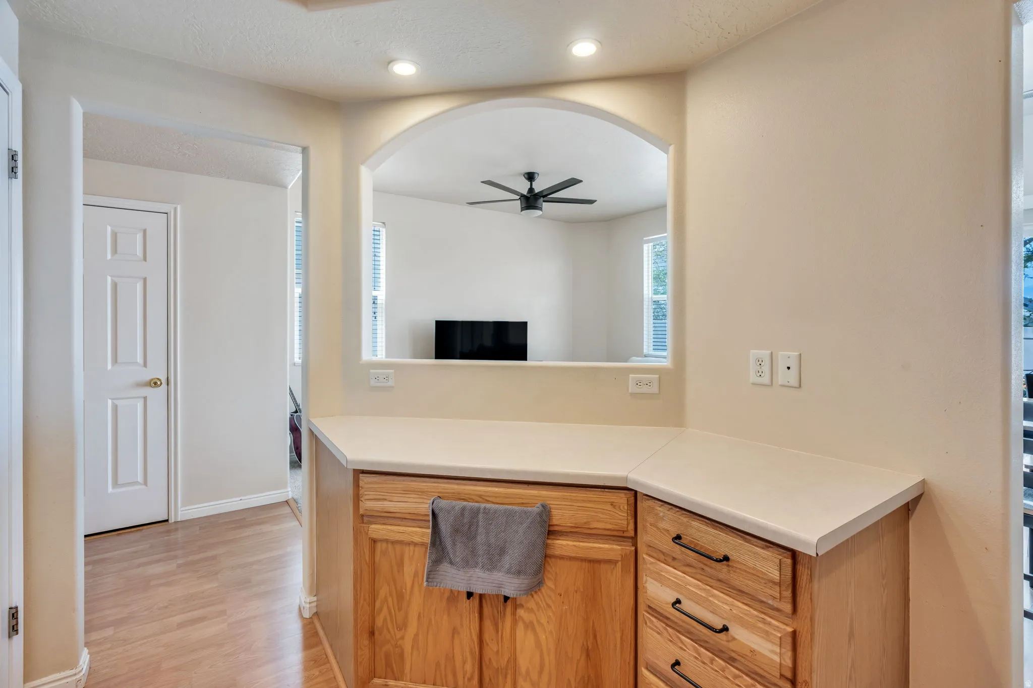 Kitchen pass-through with light wood-finish cabinetry and light-toned countertops