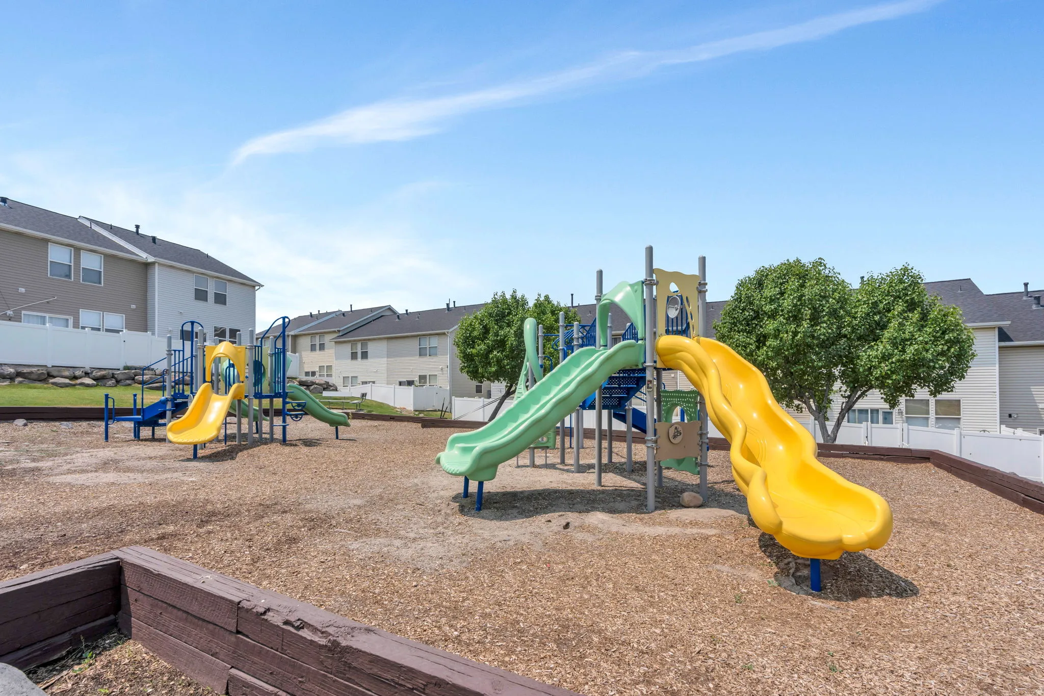 Community playground featuring multiple slides, climbing structures, and wood-chip surfacing