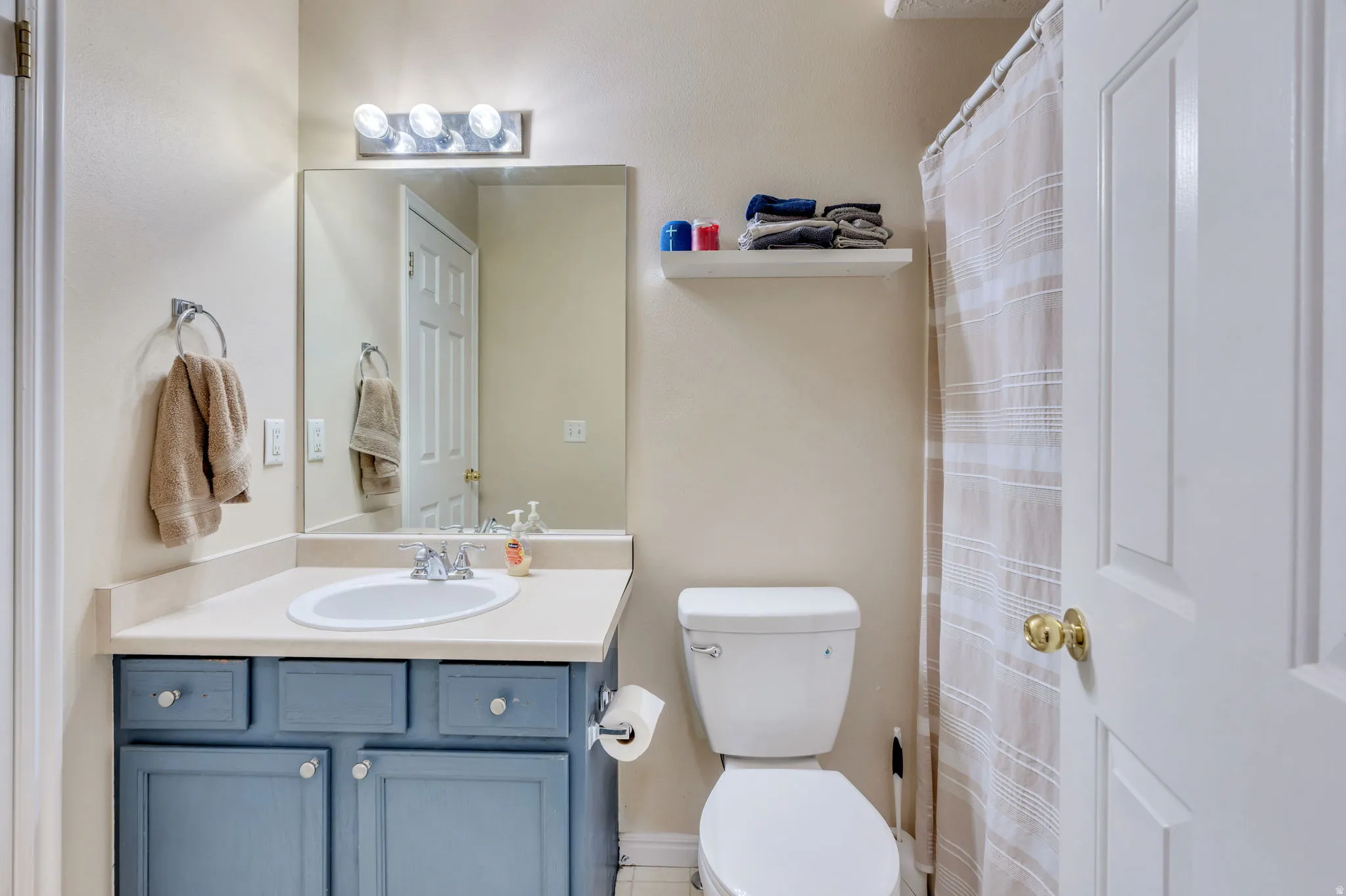 Bathroom featuring a blue painted vanity with a light-colored countertop, an oval undermount sink, and a large mirror