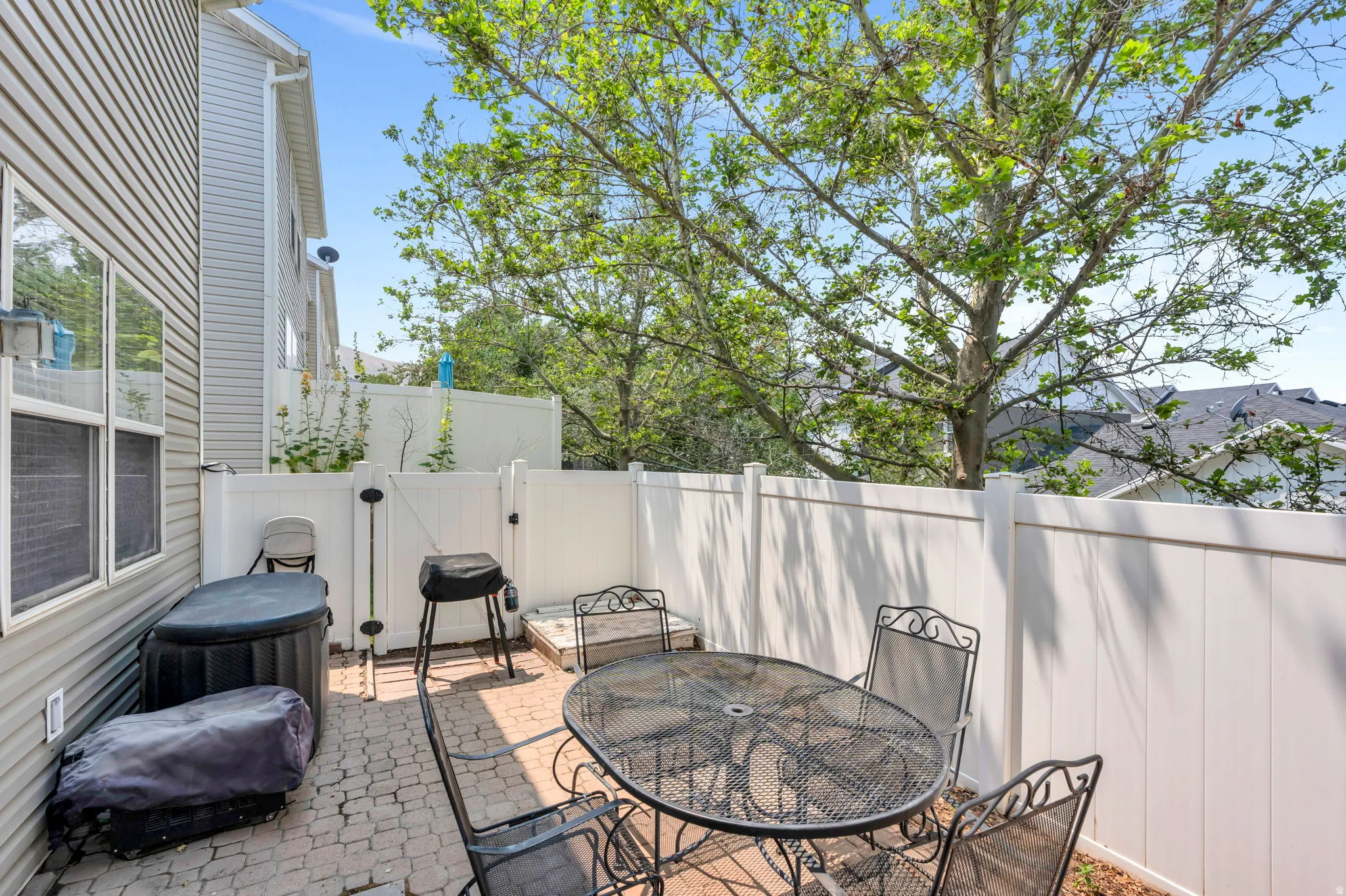 Private paver patio bordered by white privacy fencing