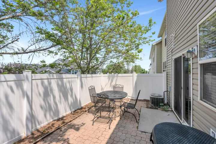 Private patio with paver flooring, enclosed by a white privacy fence