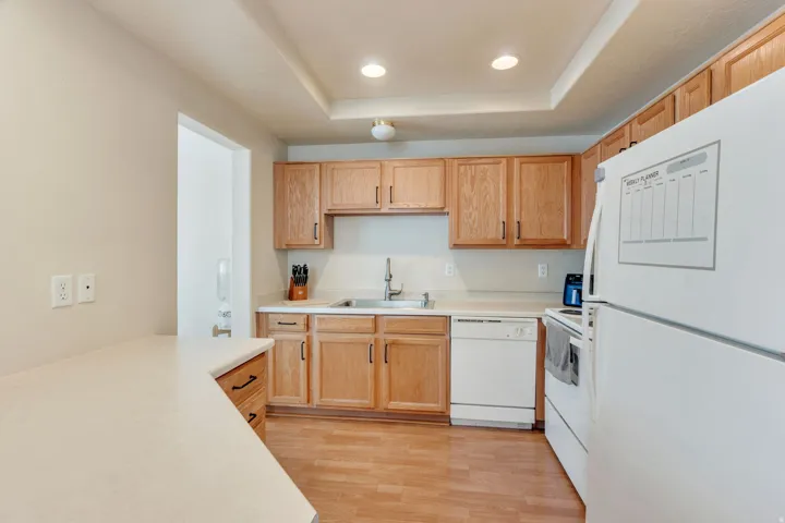 Kitchen featuring wood-finish flooring, light wood cabinetry, and white countertops