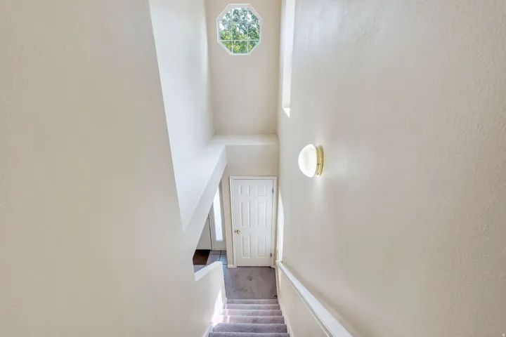 Stairwell featuring an octagonal window, high ceilings, and a wall-mounted sconce