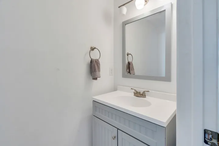 Vanity featuring a white countertop with an integrated sink, brushed nickel faucet, and beadboard-style cabinetry