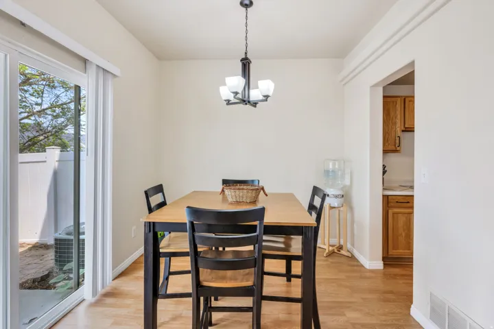 Dining area featuring wood-finish flooring, a contemporary chandelier, and direct access to an outdoor space via a glass sliding door