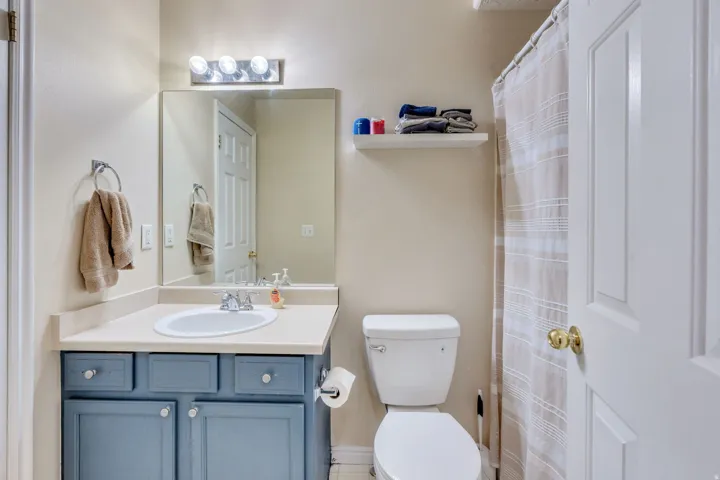 Bathroom featuring a blue painted vanity with a light-colored countertop, an oval undermount sink, and a large mirror