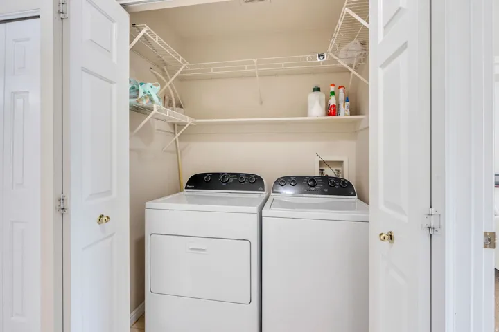 Dedicated laundry closet featuring a washer and dryer, upper wire shelving, and a built-in wall shelf