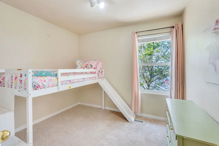 Carpeted room featuring a single window with blinds and soft pink drapes
