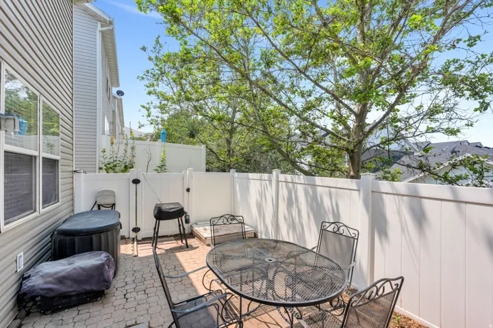 Private paver patio bordered by white privacy fencing