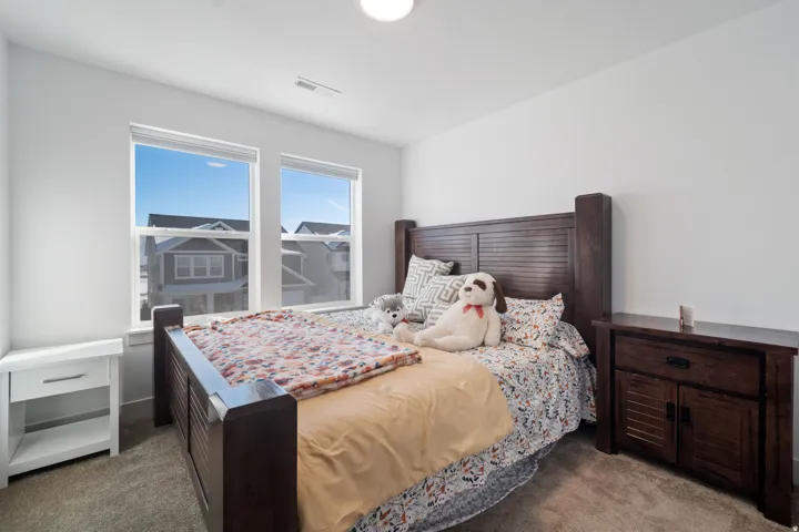 Bedroom featuring two large windows, white walls, and neutral carpet flooring