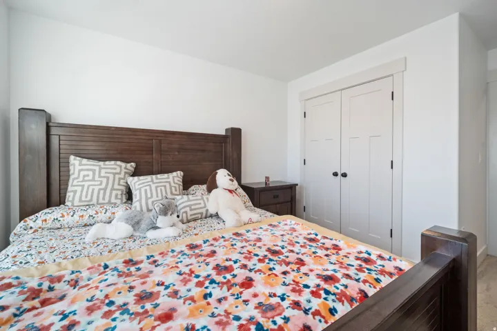 Room featuring a wood-finish headboard, white walls, and a pair of white bifold doors