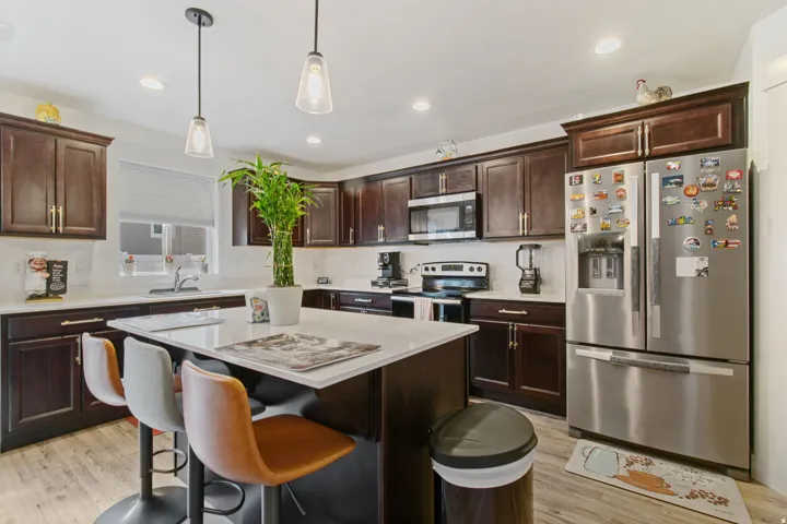Spacious kitchen featuring dark wood cabinetry, light-toned countertops, and wood-finish flooring